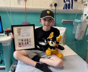 Young patient smiling while holding a stuffed animal in hospital bed