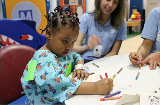 Young patient doing art activities with volunteer in hospital setting